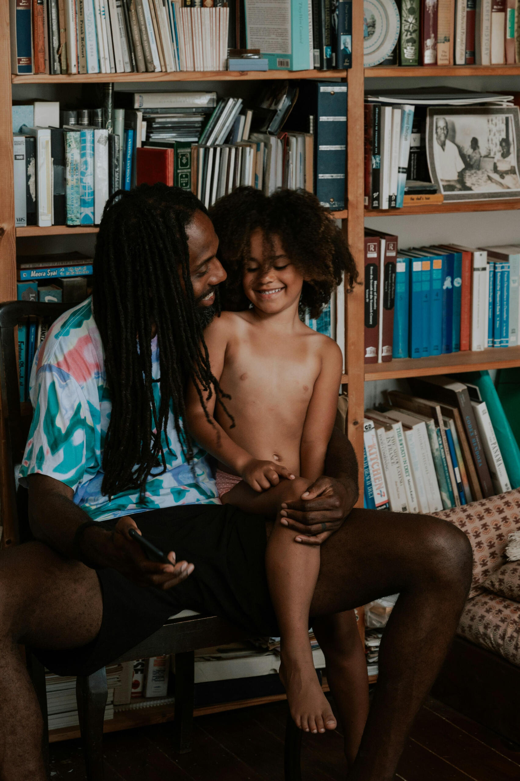 Father and child sit in front of many books
